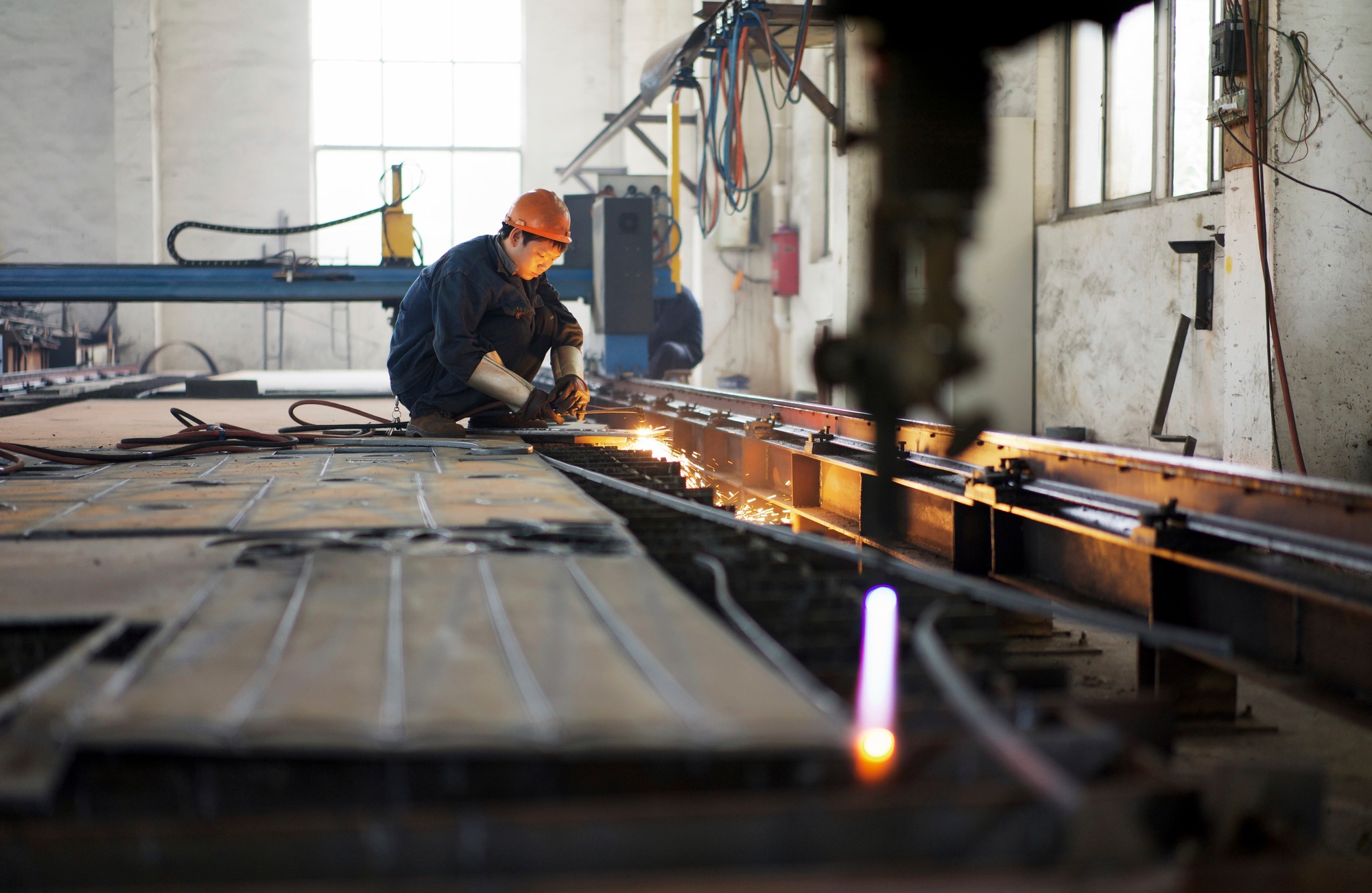 Worker using equipment in crane manufacturing facility, China